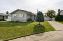 Exterior featuring light-colored siding, shake shingles, and a well-maintained lawn - 3421 135A Avenue Nw, Edmonton, AB 