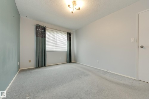 Carpeted flooring, window with blinds, ceiling-mounted light fixture, and a white interior door - 3421 135A Avenue Nw, Edmonton, AB 
