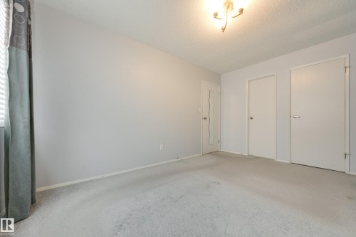 Wall-to-wall carpeting with light-toned walls and a single window with blinds - 3421 135A Avenue Nw, Edmonton, AB 