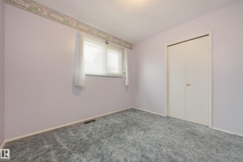 Wall-to-wall carpet flooring with white trim, a double-door closet, and a single window with blinds - 3421 135A Avenue Nw, Edmonton, AB 