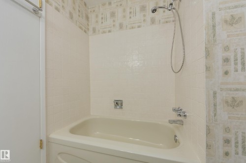Bathtub with tiled surround, chrome fixtures, and a handheld showerhead - 3421 135A Avenue Nw, Edmonton, AB 