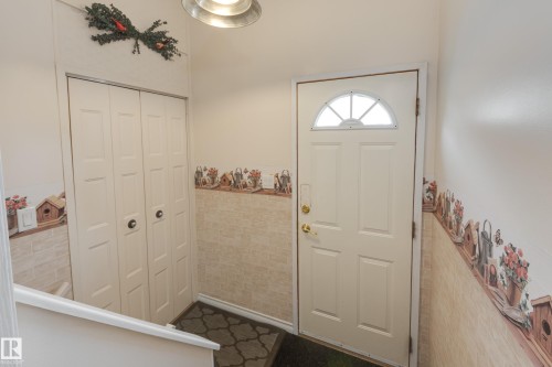 Front entry with a paneled door featuring an arched transom window, bi-fold closet doors, and recessed overhead lighting - 3421 135A Avenue Nw, Edmonton, AB 