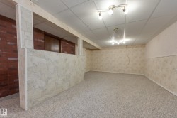 Recessed lighting fixtures illuminate a spacious area with carpet flooring and patterned wallpaper - 