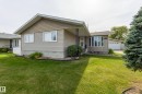 Exterior featuring a tan siding, front bay window, gabled roofline, and attached garage - 3421 135A Avenue Nw, Edmonton, AB 