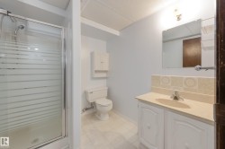 Glass-enclosed shower, white vanity with integrated sink, wall-mounted mirror, and tiled backsplash - 