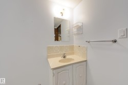 Vanity with an integrated sink, patterned tile backsplash, wall-mounted mirror, and overhead lighting - 
