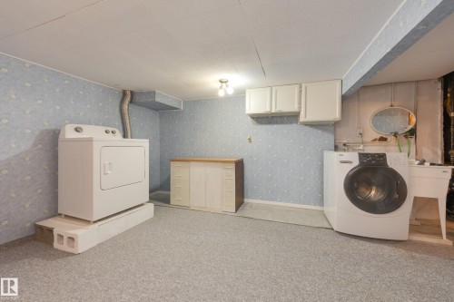 Dedicated laundry space with light-toned wall covering, white cabinetry, and overhead lighting - 3421 135A Avenue Nw, Edmonton, AB 