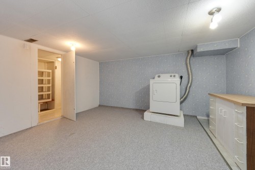 Washer and dryer appliances, light-toned carpeting, wood-finish countertop, and built-in white cabinetry - 3421 135A Avenue Nw, Edmonton, AB 