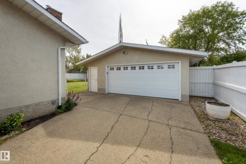 Detached garage featuring a white paneled door with multiple window inserts, stucco exterior, and a side access door - 3421 135A Avenue Nw, Edmonton, AB 