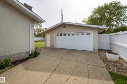 Detached garage featuring a white paneled door with multiple window inserts, stucco exterior, and a side access door - 
