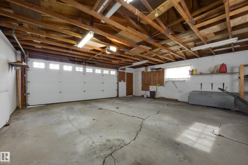 Attached two-car garage with overhead wood beam construction, integrated overhead lighting, and a white panel garage door with upper window inserts - 3421 135A Avenue Nw, Edmonton, AB 