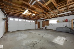 Attached two-car garage with overhead wood beam construction, integrated overhead lighting, and a white panel garage door with upper window inserts - 