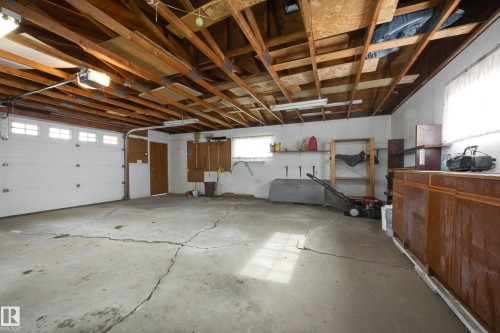 Attached garage with exposed wood ceiling joists and a white overhead door - 3421 135A Avenue Nw, Edmonton, AB 