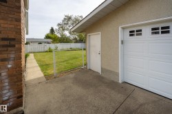 Attached garage with an overhead door featuring upper window panels, a side entry door, and a stucco exterior - 