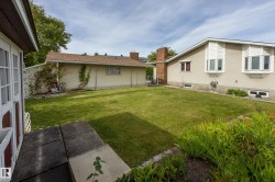 Expansive green lawn with mature landscaping and a brick chimney - 