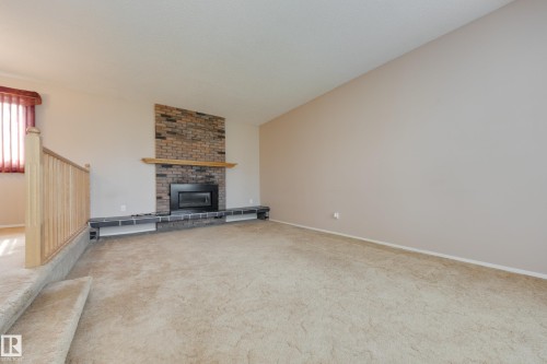 Brick fireplace with a wooden mantle and hearth - 3421 135A Avenue Nw, Edmonton, AB 