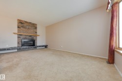 Brick fireplace with a wood mantle, integrated hearth seating, and a large window - 