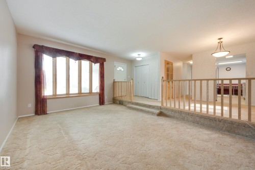 Bay window with wood trim, carpeted flooring, wood-finish railing, and ceiling-mounted light fixtures - 3421 135A Avenue Nw, Edmonton, AB 