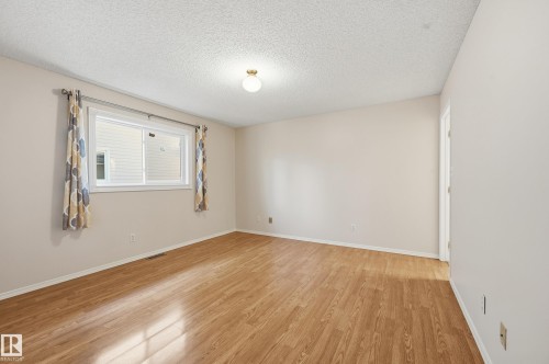 Light-filled room featuring wood-finish flooring, neutral wall paint, a single window, and a ceiling-mounted light fixture - 11102 11A Avenue Nw, Edmonton, AB 