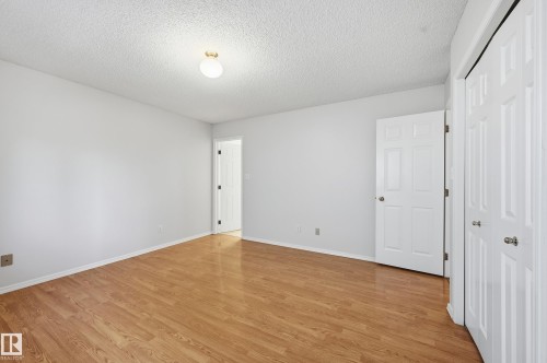 Light wood-finish flooring, white walls, and a popcorn ceiling - 11102 11A Avenue Nw, Edmonton, AB 