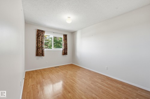 Light wood-finish flooring, white walls, and a window with a natural outdoor backdrop - 11102 11A Avenue Nw, Edmonton, AB 