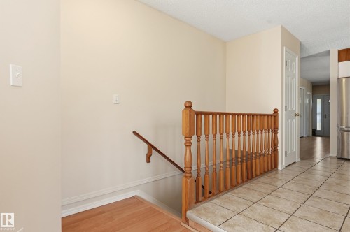 Tiled flooring entrance with wood-finish baluster, wood-finish handrail, and paneled interior door - 11102 11A Avenue Nw, Edmonton, AB 