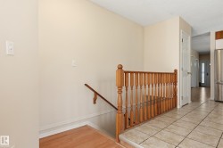 Tiled flooring entrance with wood-finish baluster, wood-finish handrail, and paneled interior door - 