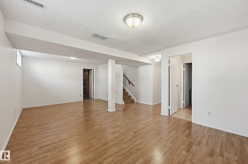 Expansive finished room featuring wood-finish flooring, recessed lighting, and a neutral color palette - 11102 11A Avenue Nw, Edmonton, AB 
