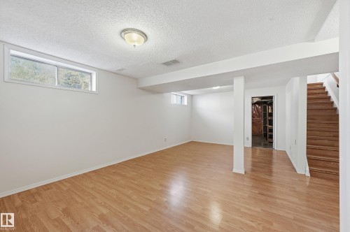 Spacious lower level featuring wood-finish flooring, recessed lighting, and multiple windows - 11102 11A Avenue Nw, Edmonton, AB 