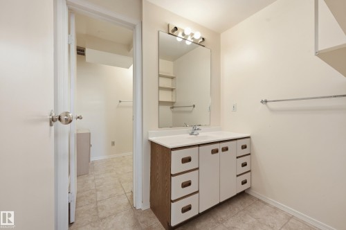 White vanity with integrated sink, chrome faucet, and mirrored cabinet - 11102 11A Avenue Nw, Edmonton, AB 