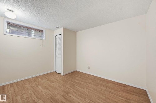 Wood-finish flooring, neutral wall tones, and bi-fold closet doors - 11102 11A Avenue Nw, Edmonton, AB 
