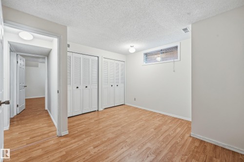 Wood-finish flooring, white bi-fold closet doors, ceiling-mounted light fixtures, and a horizontal window - 11102 11A Avenue Nw, Edmonton, AB 