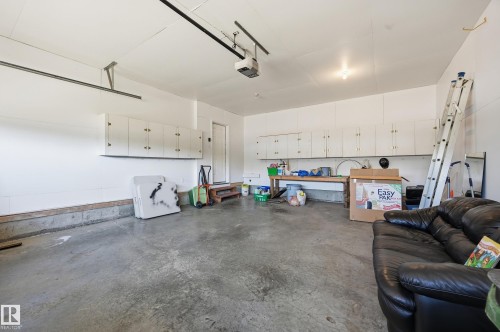 Concrete flooring garage with white walls, built-in upper cabinetry, and a workbench - 11102 11A Avenue Nw, Edmonton, AB 