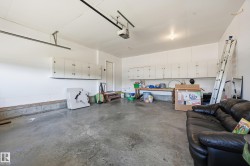 Concrete flooring garage with white walls, built-in upper cabinetry, and a workbench - 