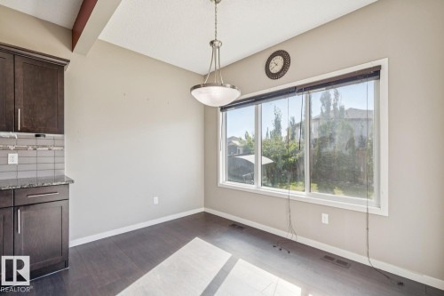Dark wood-finish flooring, dark wood cabinetry, and a full-height window - 12007 173 Avenue Nw, Edmonton, AB 