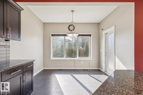 Dark wood-finish cabinetry, granite-style countertops, tile flooring, three-pane window, and a glass-paneled door - 12007 173 Avenue Nw, Edmonton, AB 