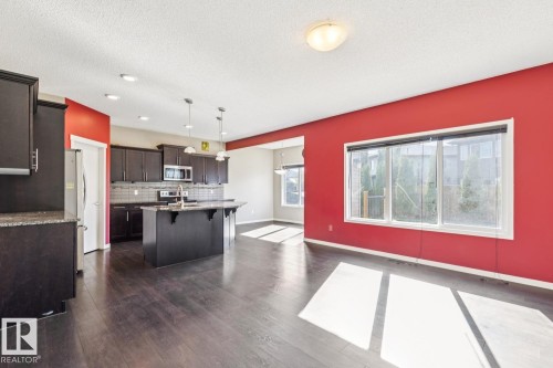 Dark wood-finish flooring, dark wood cabinetry, and a kitchen island with pendant lighting - 12007 173 Avenue Nw, Edmonton, AB 