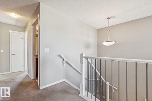Staircase featuring a white handrail and black metal spindles - 12007 173 Avenue Nw, Edmonton, AB 