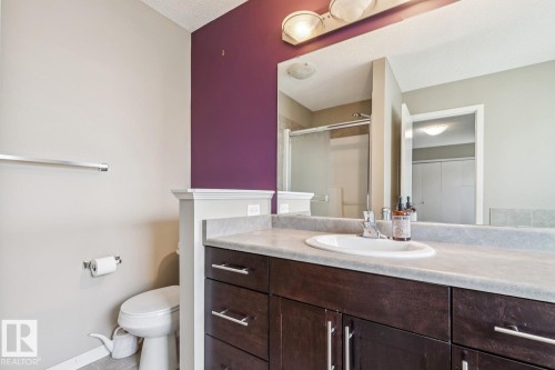 Dark wood-finish vanity with a light-toned countertop, an integrated sink, and an overhead vanity light - 12007 173 Avenue Nw, Edmonton, AB 