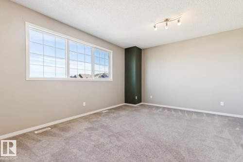 Wall-to-wall carpeting, expansive window, light neutral wall paint, accent wall, and track lighting - 12007 173 Avenue Nw, Edmonton, AB 