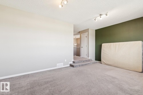 Expansive carpeted area with neutral wall tones and track lighting - 12007 173 Avenue Nw, Edmonton, AB 
