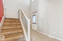 Two-story entryway featuring a carpeted staircase with white banister, tile flooring, and a door with an upper window - 12007 173 Avenue Nw, Edmonton, AB 