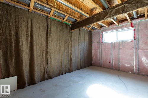 Unfinished basement space featuring exposed wood joists, concrete flooring, and an egress window - 12007 173 Avenue Nw, Edmonton, AB 