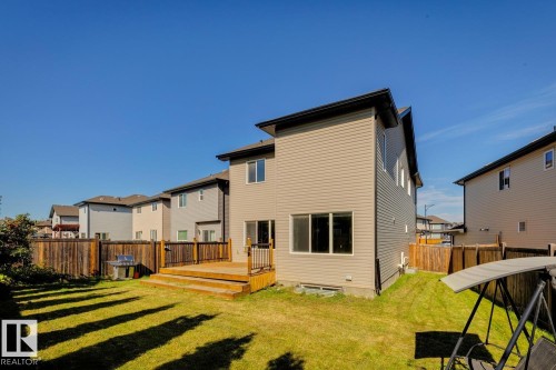 Expansive backyard with a tiered wooden deck, surrounded by a wooden privacy fence, and featuring a manicured lawn - 12007 173 Avenue Nw, Edmonton, AB 