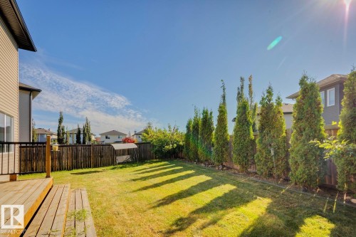 Expansive backyard featuring a wood deck, manicured lawn, and privacy fencing with mature trees - 12007 173 Avenue Nw, Edmonton, AB 