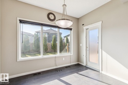 Expansive window featuring a backyard, wood-finish flooring, and a pendant light fixture - 12007 173 Avenue Nw, Edmonton, AB 