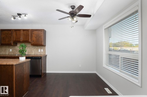Wood-finish flooring, integrated dishwasher, track lighting, ceiling fan, and large window with blinds - 441 Songhurst Place, Leduc, AB 