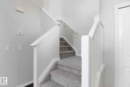 Carpeted staircase featuring white wood-finish handrails and balusters - 441 Songhurst Place, Leduc, AB 