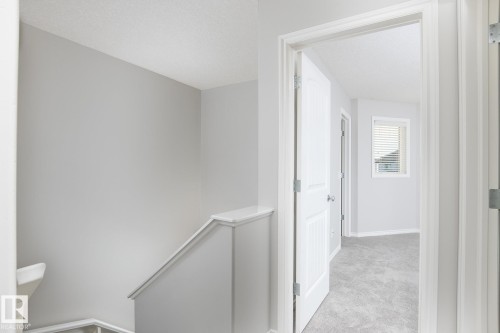 Carpeted flooring, window with blinds, interior door with paneling, painted handrail - 441 Songhurst Place, Leduc, AB 