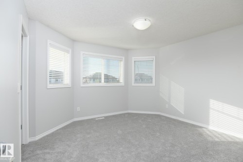 Neutral-toned walls, gray carpeting, multiple windows with blinds, and an overhead flush-mount light fixture - 441 Songhurst Place, Leduc, AB 